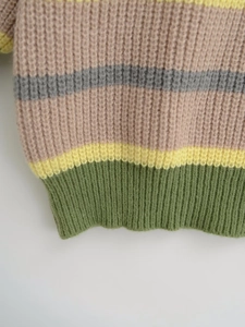 Close-up of thick striped knit sweater showing pink, grey, and yellow ribbed cuffs