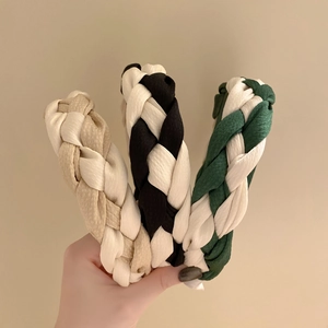 Handheld view of stylish braided fabric headbands in assorted bicolor woven designs
