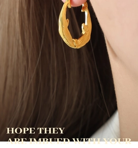 Close-up of model wearing golden irregular fish-shaped earrings in titanium steel
