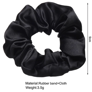 Detail of 9cm black silk satin scrunchie showing glossy fabric texture and dimensions