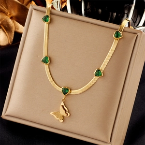 Collana a catena dorata con gemme a cuore verdi e pendente a farfalla su vassoio gioielli