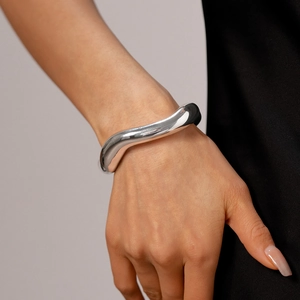 Dettaglio del bracciale rigido ondulato in argento lucido indossato sul polso sottile