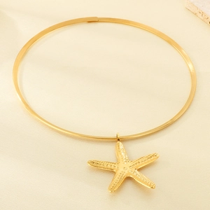 Close-up of golden starfish pendant on a metal collar over a marble and beige background