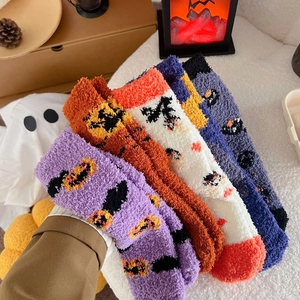 Pile of six plush Halloween socks with pumpkin, ghost, and bat patterns on coral fleece