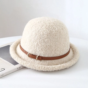 Chapeau cloche beige chic avec boucle en cuir marron posé sur une surface blanche