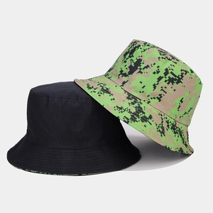 Detail of digital camouflage and solid black reversible bucket hats in cotton canvas