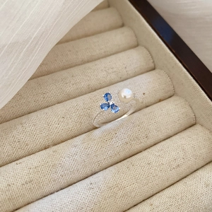 Detail of adjustable silver ring with blue pear-cut gems and a white round pearl