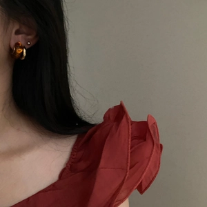 Close-up of vintage amber resin C-shaped earring worn by a model in red attire
