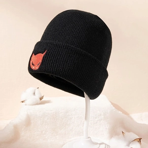 Black knitted demon beanie with red embroidery on soft white display stand