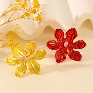 Detailed close-up of hollow metal flower rings with gold and red petals and pink centers