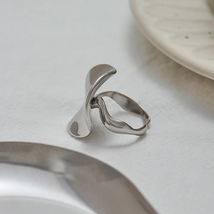 Macro shot of silver polished stainless steel ring with abstract petal design and twisted band