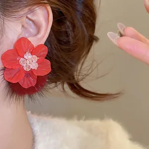 Elegant red acrylic flower earrings with plush fur balls on model for winter style