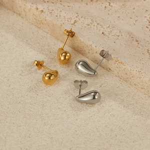 Detailed macro view of gold and silver teardrop earrings with a polished mirror finish