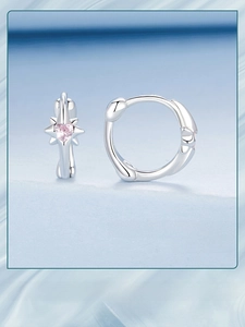 Detailed macro of silver star hoop earrings featuring a pink heart-shaped center gemstone