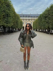 Detailed street style shot of olive green faux leather jacket with waist belt and shorts