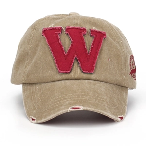 Macro detail of washed khaki cotton cap with distressed holes and red W letter patch