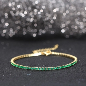 Close-up of gold plated tennis bracelet with sparkling emerald green zircon stones