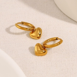 Polished golden heart-shaped hoop earrings on white textured background for daily wear