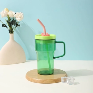 Detail of green transparent plastic cup with handle, green lid, and pink straw with ice