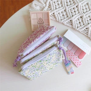 Détail de pochettes en coton à fleurs avec zips à franges en tons lilas et vert pastel