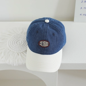 Detail of blue denim baseball cap with white brim and red CO.YRXD embroidery