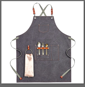 Detail view of heavy-duty canvas apron with brown leather straps and metal hardware