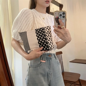 Detailed shot of black and white polka dot makeup bag held by a model for a lifestyle view