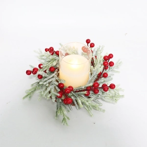 Close-up of frosted pine needles and red berries around a lit candle in a glass holder