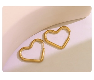 Close-up of heart-shaped gold-plated titanium steel earrings on a soft aesthetic background