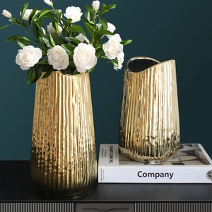 Set of two gold plated ceramic vases with vertical wave texture and white roses