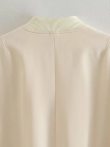 Detail view of the ribbed stand collar and smooth beige fabric on the women jacket