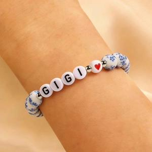Dettaglio macro del braccialetto GIGI con perle in ceramica blu e ciondolo a cuore rosso