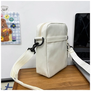 Detail view of white nylon messenger bag featuring black buckles and adjustable strap