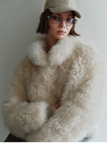 Close-up of thick beige faux fox fur texture with curly granular wool on a winter vest