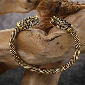 Golden Viking dragon head cuff bracelet with braided texture on a rustic wood base