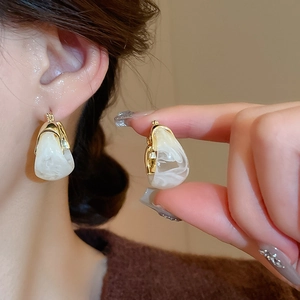 Detail of vintage U-shaped resin earrings with gold accents on a model's ear