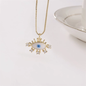 Elegante goldene Evil Eye Halskette mit blauen Kristallen und Muscheln auf weißem Hintergrund