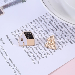 Detailed front and back view of house enamel pins with golden finish and needle clasp