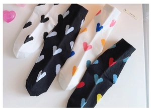 Close-up of four pairs of cotton socks featuring colorful heart patterns in black and white