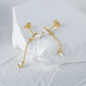 Detail of S925 silver long gold earrings with teardrop zircon and white opal stone