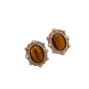 Vintage gold earrings featuring oval tiger eye stones and white pearls on a clean background
