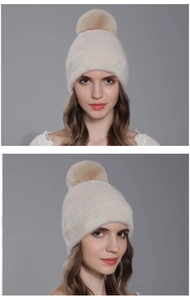Vue détaillée du bonnet en maille beige d'hiver avec un grand pompon en fausse fourrure