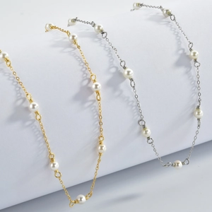 Macro shot of gold and silver beaded necklaces with elegant white pearls on a white background