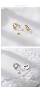 Detail of gold and silver heart studs with multi-color rhinestones on stone background