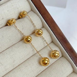 Detailed view of 18K gold plated long chain drop earrings with triple polished spheres