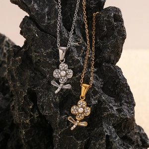 18K vergoldete Blumenkette mit Perlen und Zirkonia auf schwarzem Felsen präsentiert