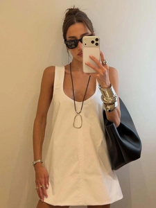 Mini-robe blanche sans manches minimaliste avec un grand sac fourre-tout noir en cuir