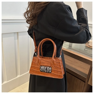 Close-up of brown crocodile texture and ZMIEBO lettering on a stylish square handbag