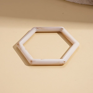 Detailed view of hexagonal resin bangle with beige marble pattern and polished finish