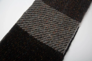 Macro shot of twill weave texture and colorful nep yarn on deep grey wool blend scarf